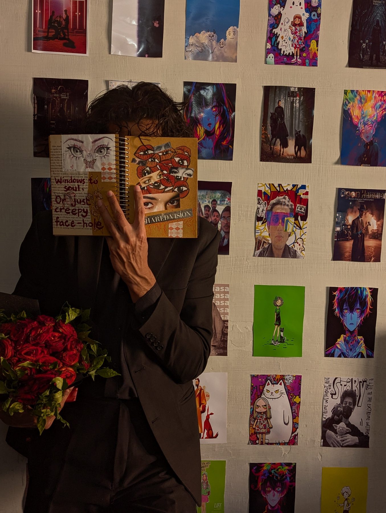 Holding a sketchbook in front of a wall of drawings